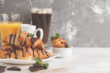 Fresh breakfast croissants with chocolate syrup, orange juice and cocoa with marshmelow. Copy space. French cuisine dessert concept.