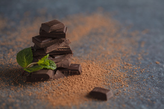 Stack of dark chocolate with mint leaf. Dark background, copy space. Macro