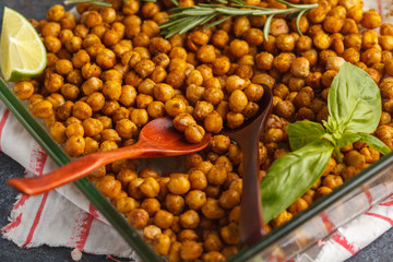Healthy snack - baked spicy chickpeas in a glass dish. Healthy vegan food concept.