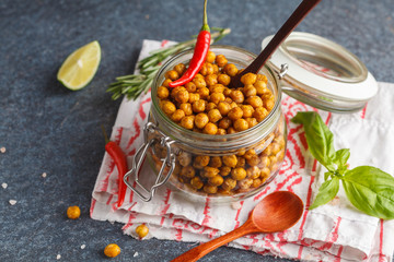 Healthy snack - baked spicy chickpeas in a glass jar. Healthy vegan food concept.
