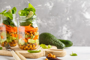 Homemade green salad in a glass jar with baked chickpeas, guacamole and vegetables, copy space. Healthy diet detox vegan food concept.