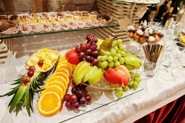 Close-up photo of a huge variety of fruits and sweet desserts on the wedding banquet.
