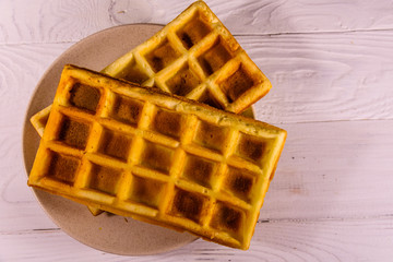 Ceramic plate with belgian waffles on wooden table. Top view