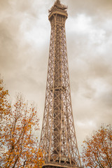 Eiffel tower with autumn trees and clouds - Paris, France.