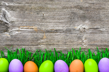Green grass and eggs, painted easter eggs on wooden background