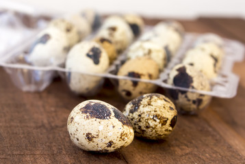 Quail eggs in a transparent plastic container on a wooden kitchen table