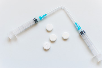 Syringes and pills on a white background.