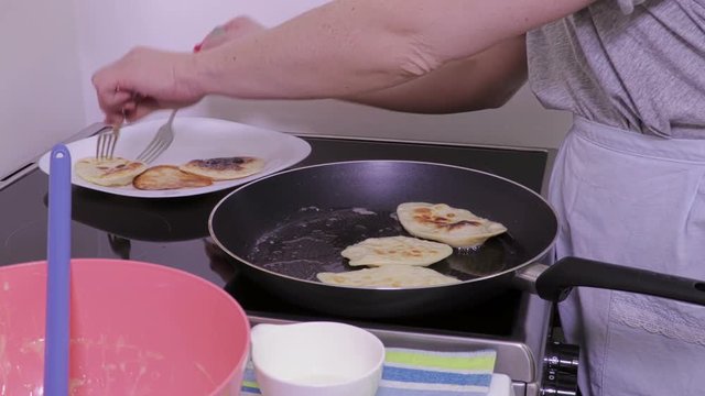Woman put finished pancakes on plate