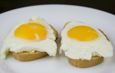 Two sandwiches with egg on a white plate.