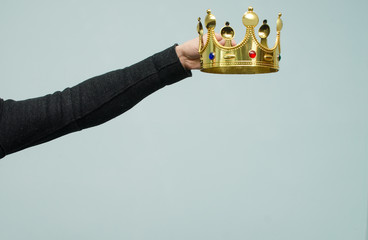 Hands are wearing a golden crown on head copy space isolated on light blue background. Winner....
