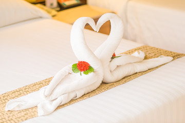 Swan couple put on honeymoon bed look like heart shape with flower petals for honeymoon lover in the room make romantic feeling.