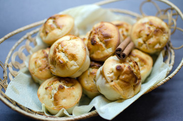 Muffins with apple and cinnamon in basket decorated with cinnamon piece on grey background
