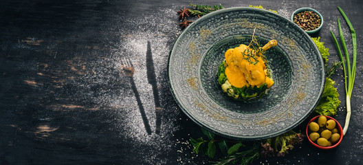 Baked rabbit with broccoli and spinach. Top view. On a black wooden background. Copy space.
