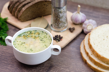 Mushroom soup with croutons in a white dish is on a wooden table.