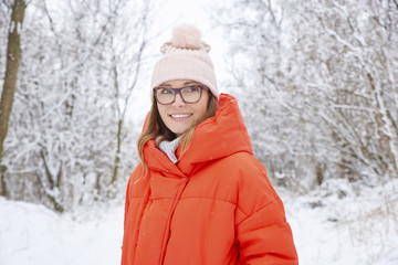 Fototapeta na wymiar Woman walking outdoor in winter. Close-up portrait shot a happy woman wearing hat and warm coat while standing outdoor and enjoy snowy weather. 