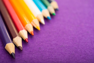 Fototapeta premium Nine multicolored pencils on a purple felt background. Different colored pencils with space for text. Back to school. Art lessons.