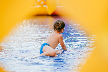 Fototapeta premium the boy bathes in the children's pool. boy playing in the inflatable pool. through hole, frame.