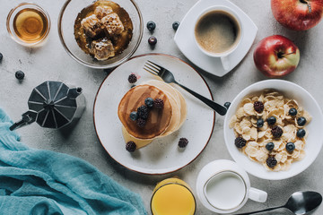 top view of tasty healthy breakfast with pancakes, muesli and fruits on grey