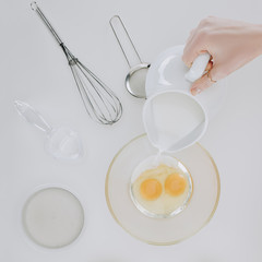 top view of person pouring milk while cooking pancakes isolated on grey