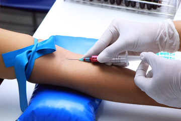 Nurse pricking needle syringe in the arm patient drawing blood sample for blood test. Medical care...
