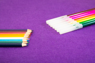 Fototapeta premium Seven multicolored felt pens and nine different colored pencils on a purple felt background with space for text. Back to school. Art lessons.