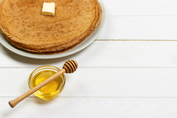 Fried crepes with honey on white wooden table. top view with copy space