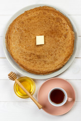 Hot pancakes with butter and honey on a plate. Breakfast with tea and crepes