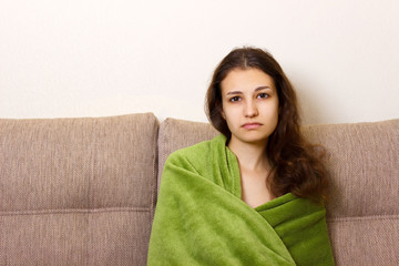 Depressed young woman sitting on sofa. Stressed and upset adolescent girl feels emotional...