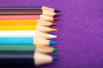 Fototapeta premium Nine multicolored pencils on a purple felt background. Different colored pencils with space for text. Back to school. Art lessons.