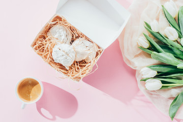 top view of white tulips, delicious meringue cookies and cup of coffee on pink