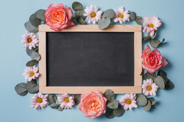 Blackboard, floral pattern of roses buds, eucalyptus, camomiles and petals background. Flat lay, Top view.