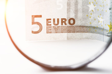 Five euro bill through a magnifying glass. Closeup, toned