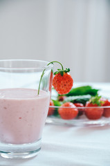 Strawberry milkshake in glass garnished with fresh strawberries on white background