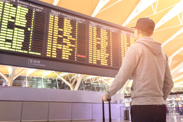 Passenger looking at flights information board in airport terminal