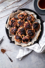 Cinnabon buns with chocolate cream on gray concrete background. Rustic styling; copy space. Vertical composition.