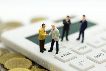 Miniature people: Businessman stand on calculator, calculation tax monthly/yearly. Image use for Tax calculation every year for everyone.