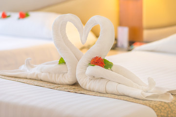 Fototapeta na wymiar Swan couple put on honeymoon bed look like heart shape with flower petals for honeymoon lover in the room decoration make romantic feeling.