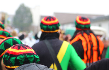 people with jamaica caps at carnival procession, rear view - obrazy, fototapety, plakaty