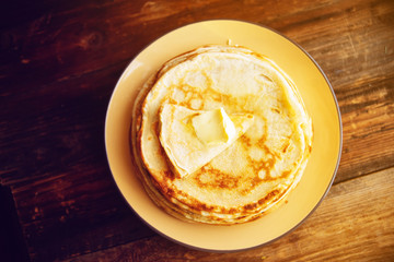 Russian Maslenitsa, Shrovetide, pancake week, carnival, shrove, pancake day. a stack of pancakes with butter upstairs on plate, on wooden background, close-up