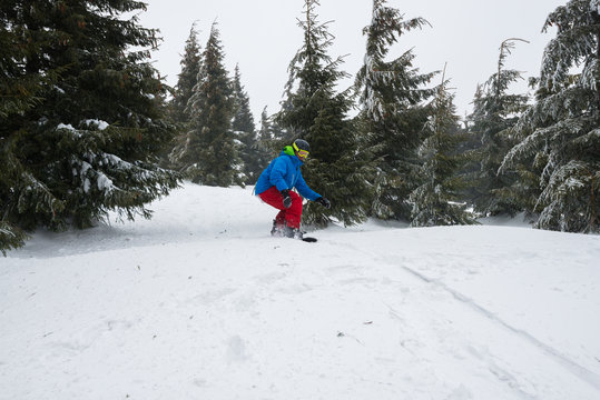 Snowboarder, preparing to jump, while rides down a mountain slope