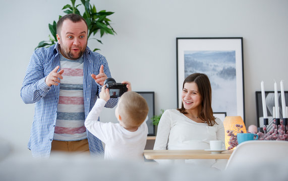 Photo of young son photographing father, mother sitting at table