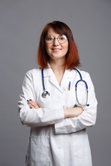Fototapeta premium Image of smiling brunette doctor in white coat and with phonendoscope in glasses