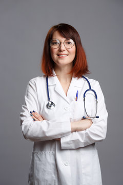 Image of smiling brunette doctor in white coat and with phonendoscope in glasses