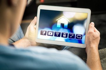 Man using smart home application in tablet to control house appliances. Internet of things (IOT)...