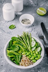 Green vegetarian buddha bowl salad with fresh vegetables and quinoa, spinach, avocado, asparagus, cucumber, edamame beans