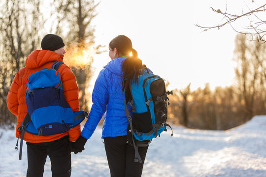 Image from back of man and woman with backpacks in winter forest