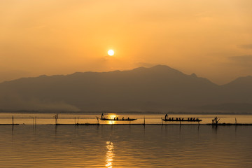 Naklejka na ściany i meble landscape view - boatman paddle boat in the lagoon lake.(Kwan phayao) in evenign time at phayao thailand