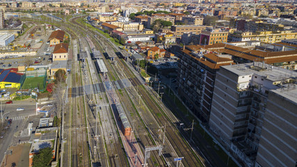 Fototapeta premium Aerial view of the Tuscolana station in Rome, in Italy. Around the rails there are the palaces and streets of the Italian city. The railroad tracks are made of steel.