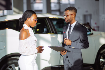african Car dealer showing vehicle to black woman