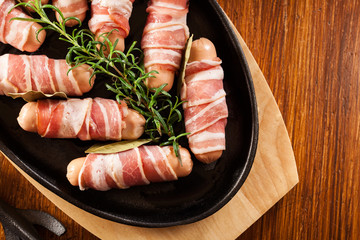 Raw mini sausages wrapped in smoked bacon